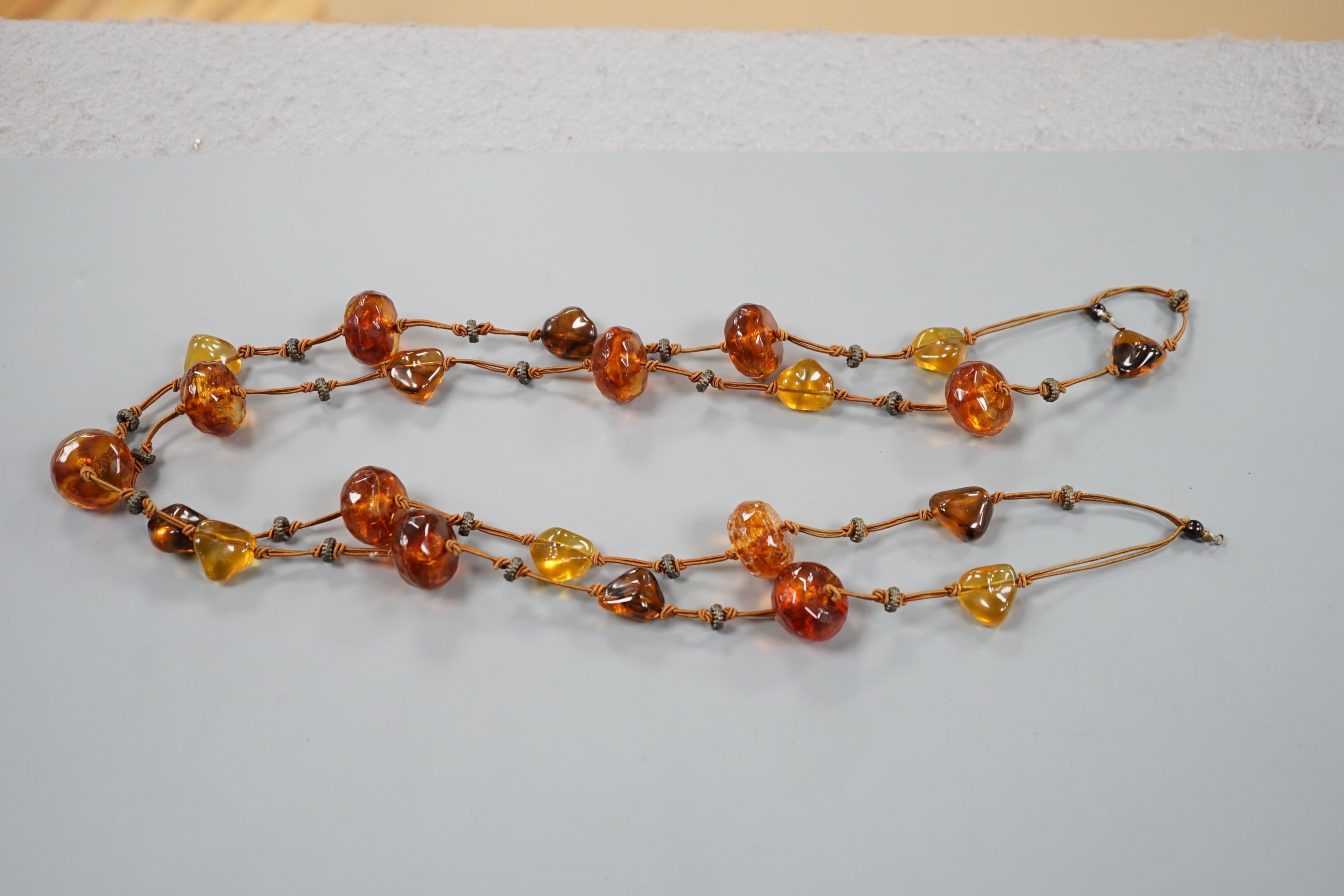 A single strand facetted and pebble amber necklace, 138cm.